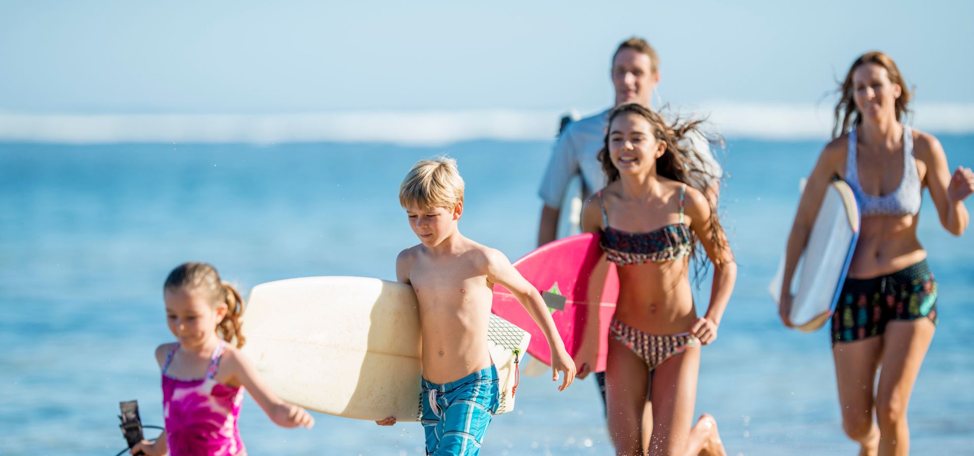 Family surfing at a sunny beach, protected with Squirrel’s Nut Butter – natural anti-chafe salve for surfers, prevents chafing and blisters, water-resistant, long-lasting, and skin-friendly